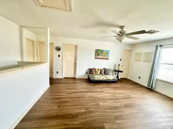 a view of a bedroom with wooden floor and ceiling fan