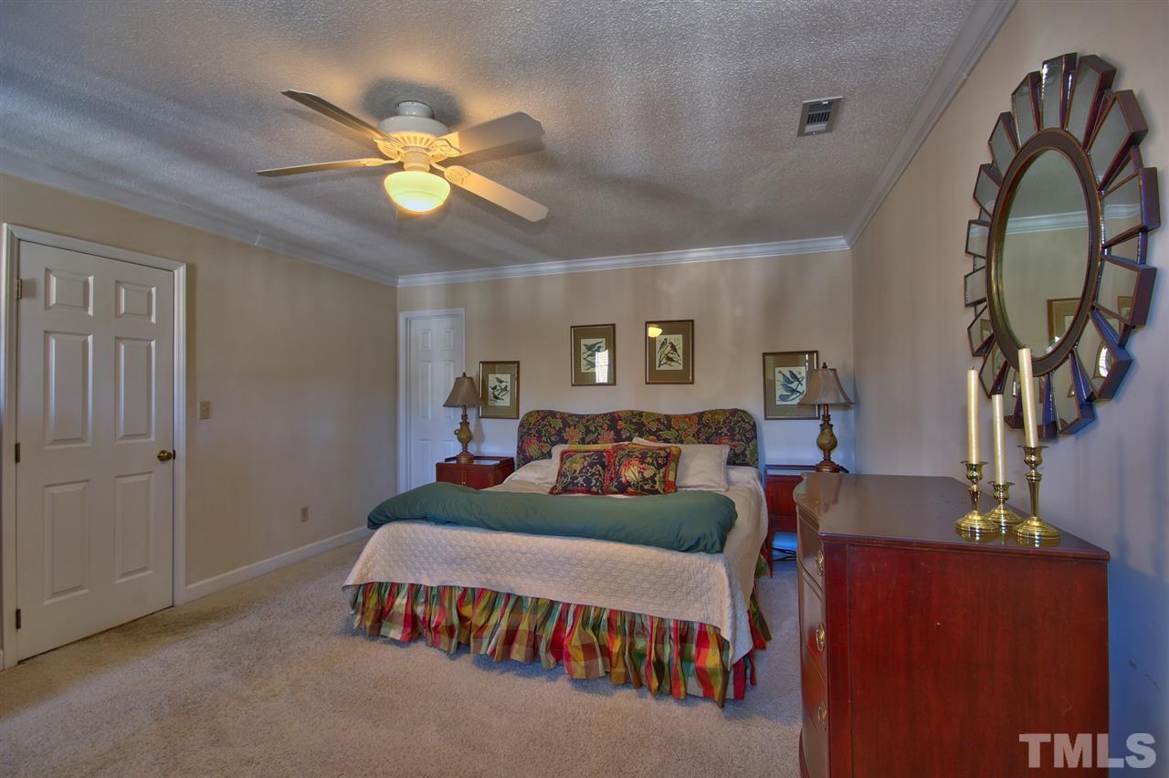 7141 Kinross Drive Raleigh, NC 27613 - Photo 11 of 19 a bedroom with a bed table and a chandelier