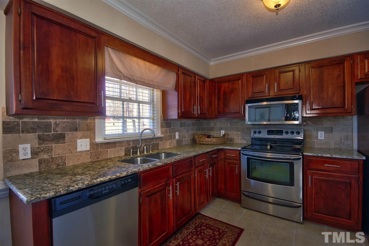 7141 Kinross Drive Raleigh, NC 27613 - Photo 5 of 19 a kitchen with kitchen island granite countertop wooden cabinets stainless steel appliances a sink and a window