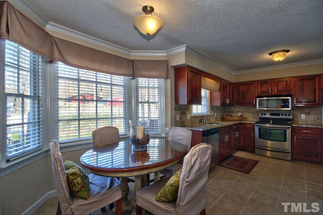 7141 Kinross Drive Raleigh, NC 27613 - Photo 7 of 19 a kitchen with stainless steel appliances granite countertop a stove a refrigerator a sink a dining table and chairs