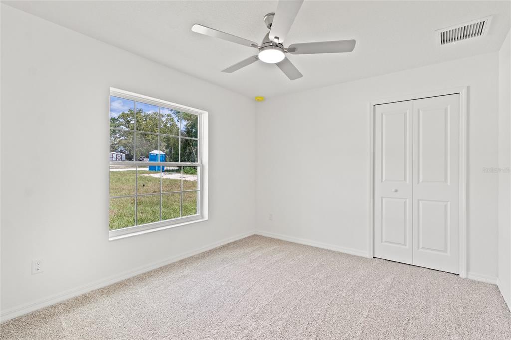 15333 Honeycreeper Road Brooksville, FL 34614 - Photo 13 of 19 an empty room with chandelier fan and windows
