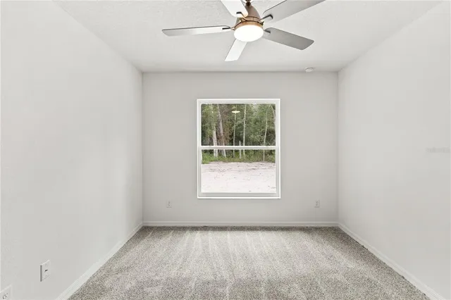 an empty room with a window and a fan