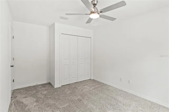 an empty room with a fan & a ceiling fan