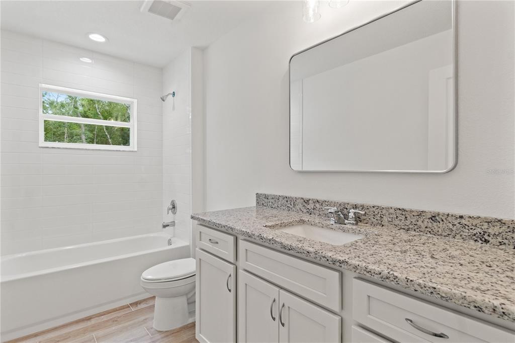 15333 Honeycreeper Road Brooksville, FL 34614 - Photo 17 of 19 a bathroom with a granite countertop sink a toilet and a bathtub