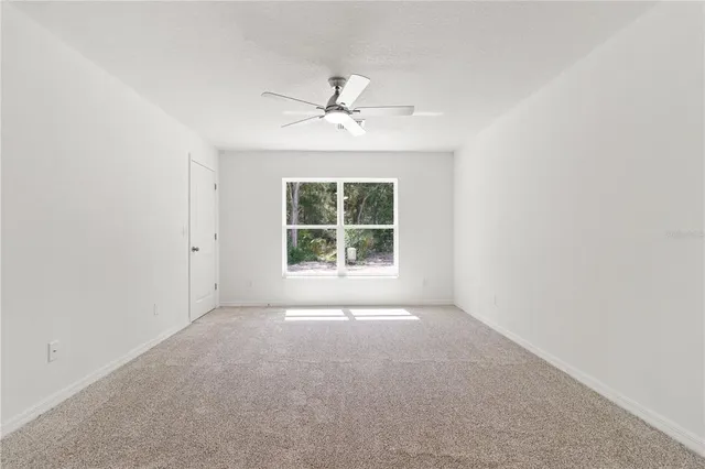 an empty room with windows and ceiling fan