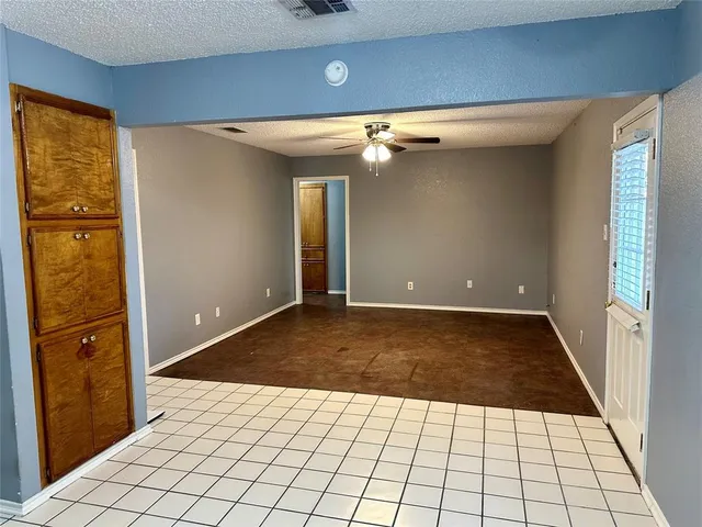 an empty room with a chandelier fan and windows