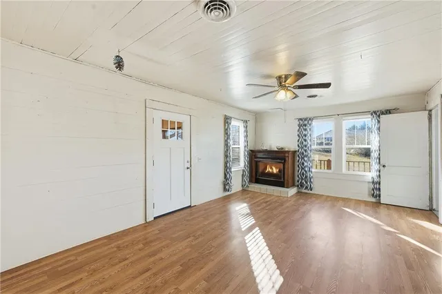 a view of an empty room with a window and a kitchen