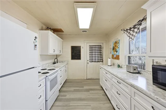 a large white kitchen with granite countertop a sink a window stainless steel appliances and cabinets