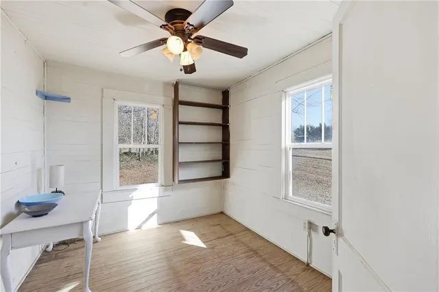 an empty room with windows and fan