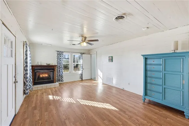 a view of an empty room with wooden floor fireplace and a window
