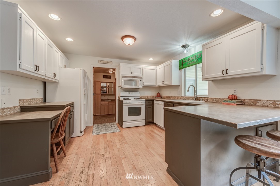 2633 189th Street Southeast Bothell, WA 98012 - Photo 11 of 35 a kitchen with stainless steel appliances granite countertop a stove top oven a sink dishwasher and a refrigerator with wooden floor