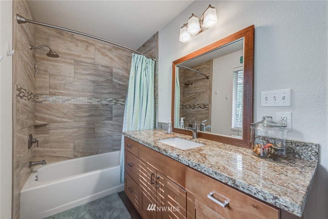 2633 189th Street Southeast Bothell, WA 98012 - Photo 23 of 35 a bathroom with a granite countertop sink and a mirror