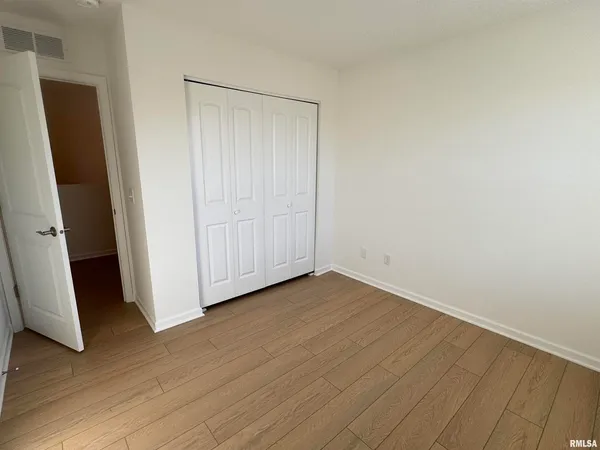 an empty room with wooden floor and closet
