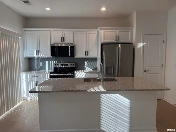 a kitchen with granite countertop a refrigerator and a stove top oven