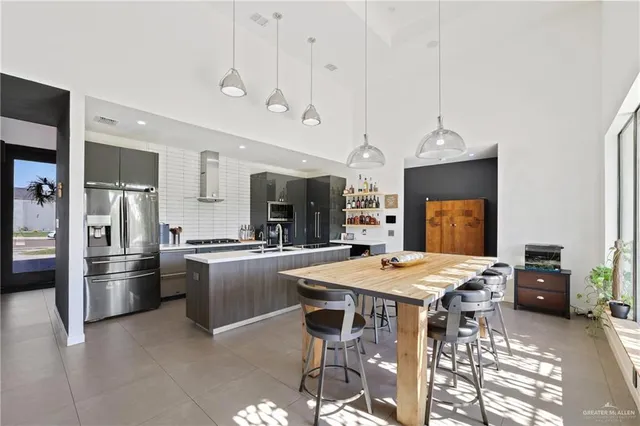 a kitchen with stainless steel appliances kitchen island granite countertop a table chairs and a refrigerator