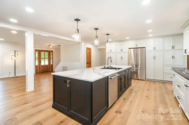 a large kitchen with granite countertop a large counter top and stainless steel appliances