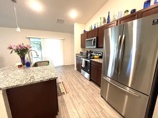 a kitchen with stainless steel appliances granite countertop kitchen island wooden floor and chairs