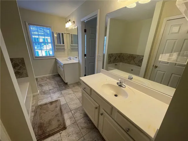 a spacious bathroom with a bathtub sink and mirror