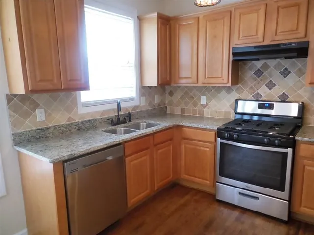 a kitchen with stainless steel appliances granite countertop a stove a sink and a microwave