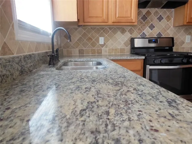 a kitchen with granite countertop a sink stainless steel appliances and cabinets