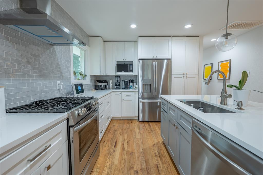 864 Peavy Road Dallas, TX 75218 - Photo 9 of 21 Modern kitchen featuring stainless steel appliances, white cabinetry, a light gray subway tile backsplash, white countertops, and wood-finish flooring