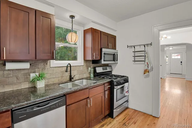 a kitchen with granite countertop wooden cabinets a stove top oven a sink and dishwasher