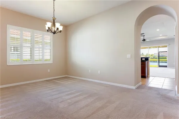 an empty room with chandelier fan and windows