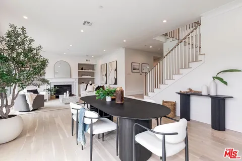 a kitchen with stainless steel appliances kitchen island a large white table chairs and a refrigerator