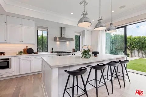 a large kitchen with stainless steel appliances a lot of counter space and a view of living room