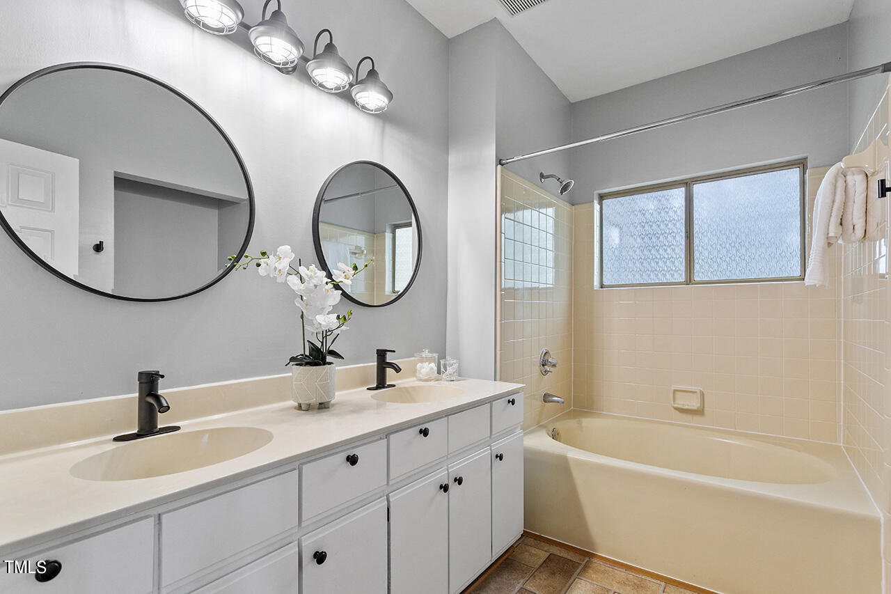 6011 Winterpointe Lane, Unit 104 Raleigh, NC 27606 - Photo 22 of 31 a bathroom with 2 sink tub and a mirror