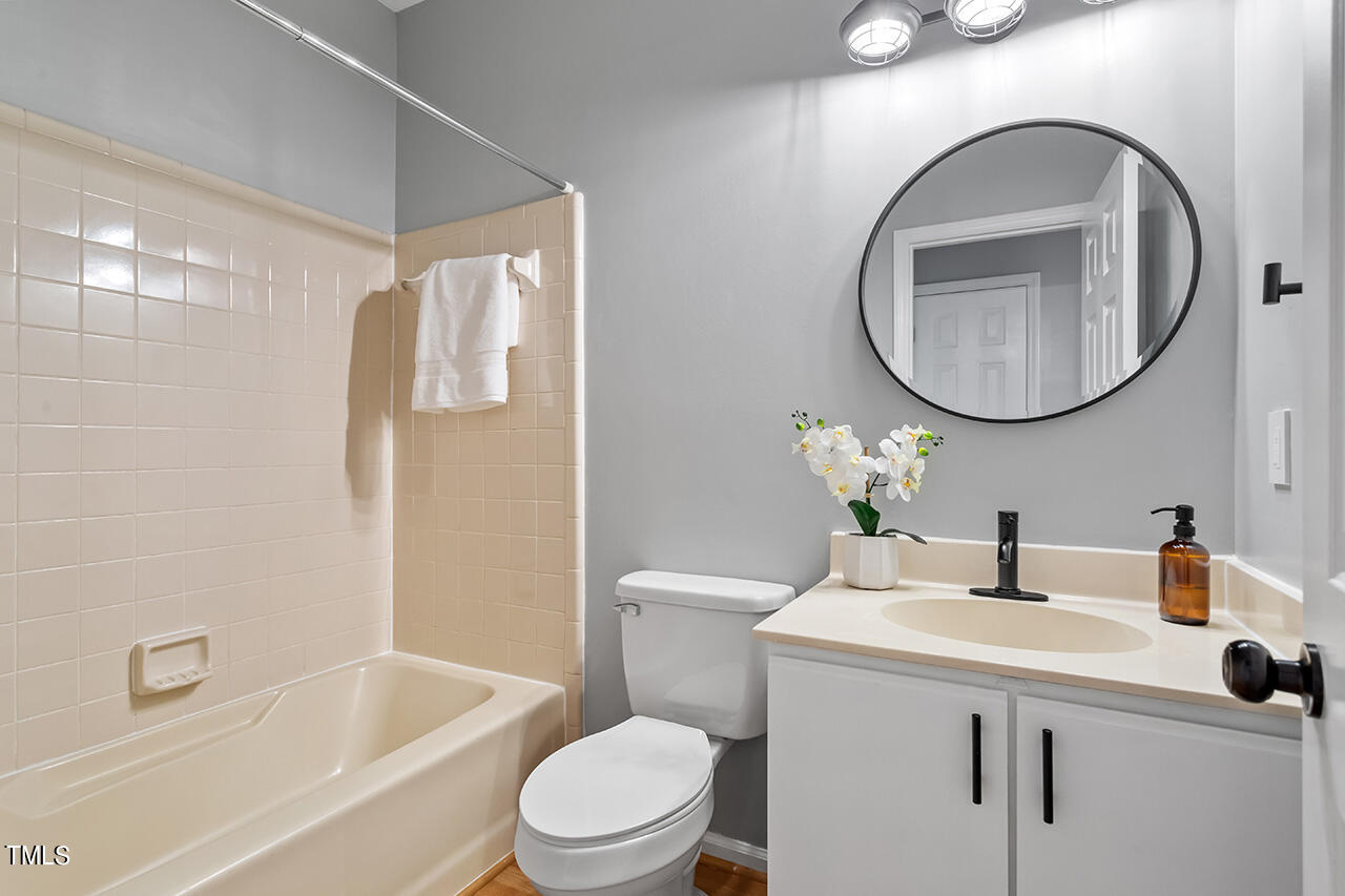 6011 Winterpointe Lane, Unit 104 Raleigh, NC 27606 - Photo 27 of 31 a bathroom with a sink a toilet and a mirror