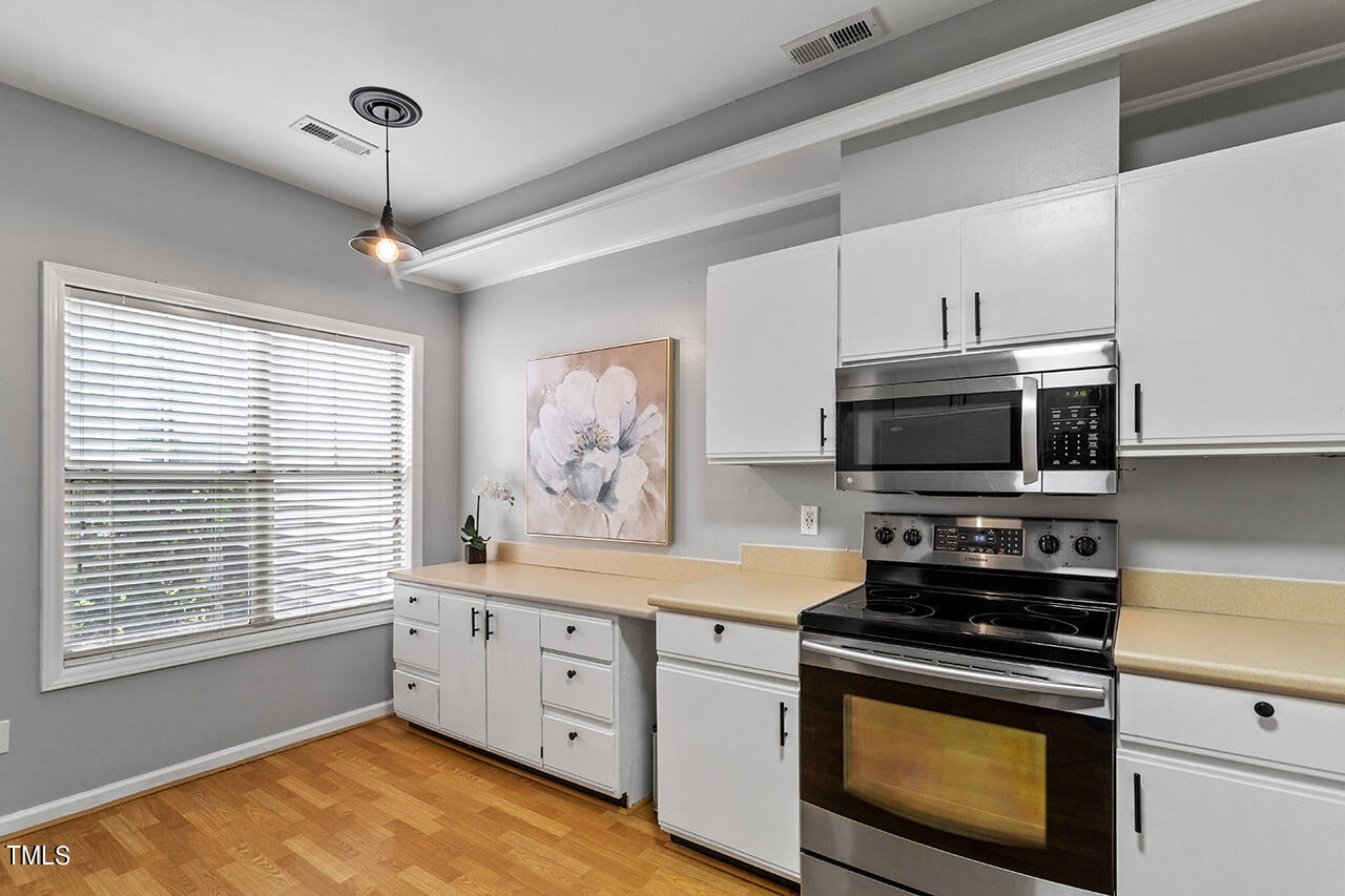 6011 Winterpointe Lane, Unit 104 Raleigh, NC 27606 - Photo 10 of 31 a kitchen with stainless steel appliances a stove a sink and a microwave