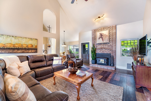 7343 North Sawtooth Cv Road Vernal, UT 84078 - Photo 5 of 64 Spacious living area featuring vaulted ceilings, a brick fireplace with a wood-burning insert, LVP flooring, and a ceiling fan