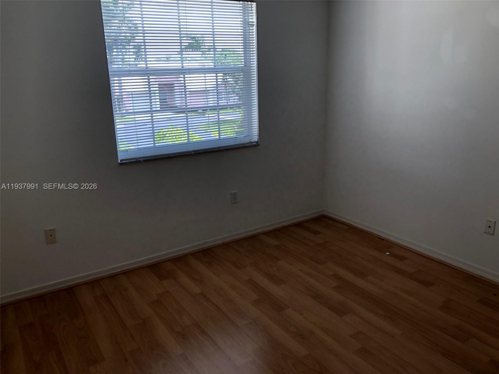 11274 Southwest 64th Lane Miami, FL 33173 - Photo 19 of 34 an empty room with wooden floor and windows