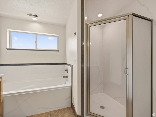 1279 West 1500th Street North Mapleton, UT 84664 - Photo 44 of 83 Bathroom featuring a shower enclosure with a clear glass door and brushed metal frame, a rectangular built-in tub with white surround, a horizontal window, recessed lighting, and tile flooring