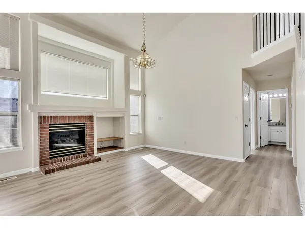 a view of a livingroom with a fireplace wooden floor and windows