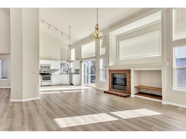 a view of an empty room with wooden floor fireplace and a window