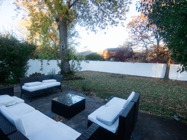 a view of a patio with couches table and chairs with plants and trees