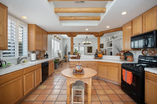 a kitchen with stainless steel appliances granite countertop a stove top oven a refrigerator a sink a dining table and chairs with wooden floor