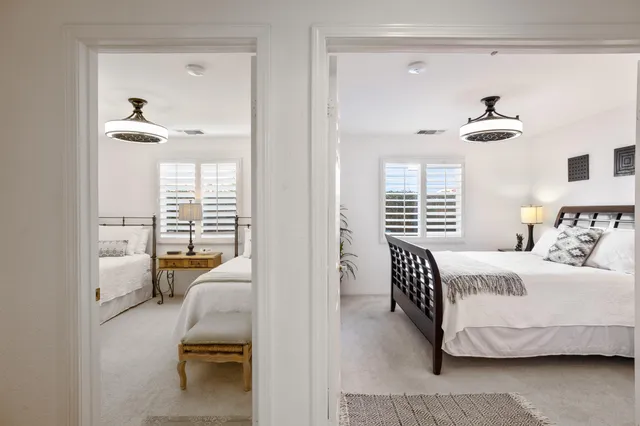 a bedroom with two beds chandelier and a window