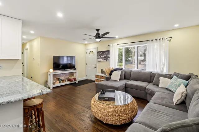 a living room with furniture a ceiling fan and a flat screen tv