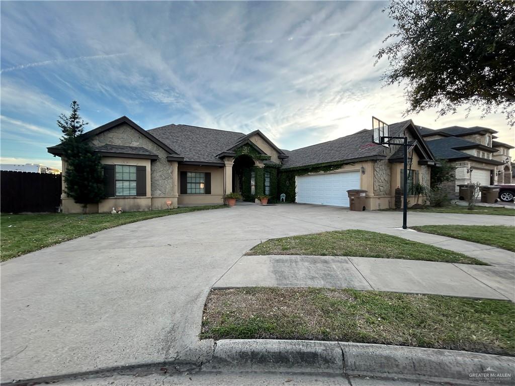 View of front of home featuring driveway, an attached garage, stucco siding, and stone siding