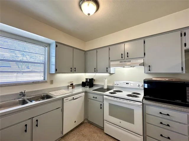 a kitchen with granite countertop white cabinets sink and appliances