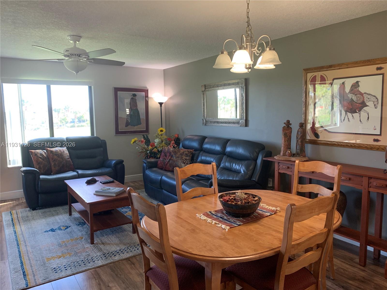 5463 Southeast Miles Grant Road, Unit 210 Stuart, FL 34997 - Photo 17 of 53 a living room with furniture a chandelier and a flat screen tv