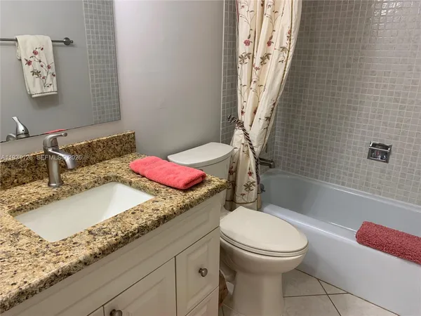 a bathroom with a bath tub sink mirror vanity and toilet