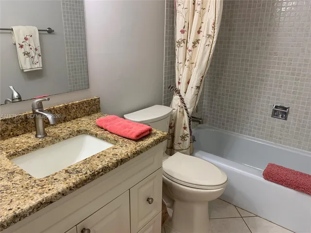a bathroom with a bath tub sink mirror vanity and toilet
