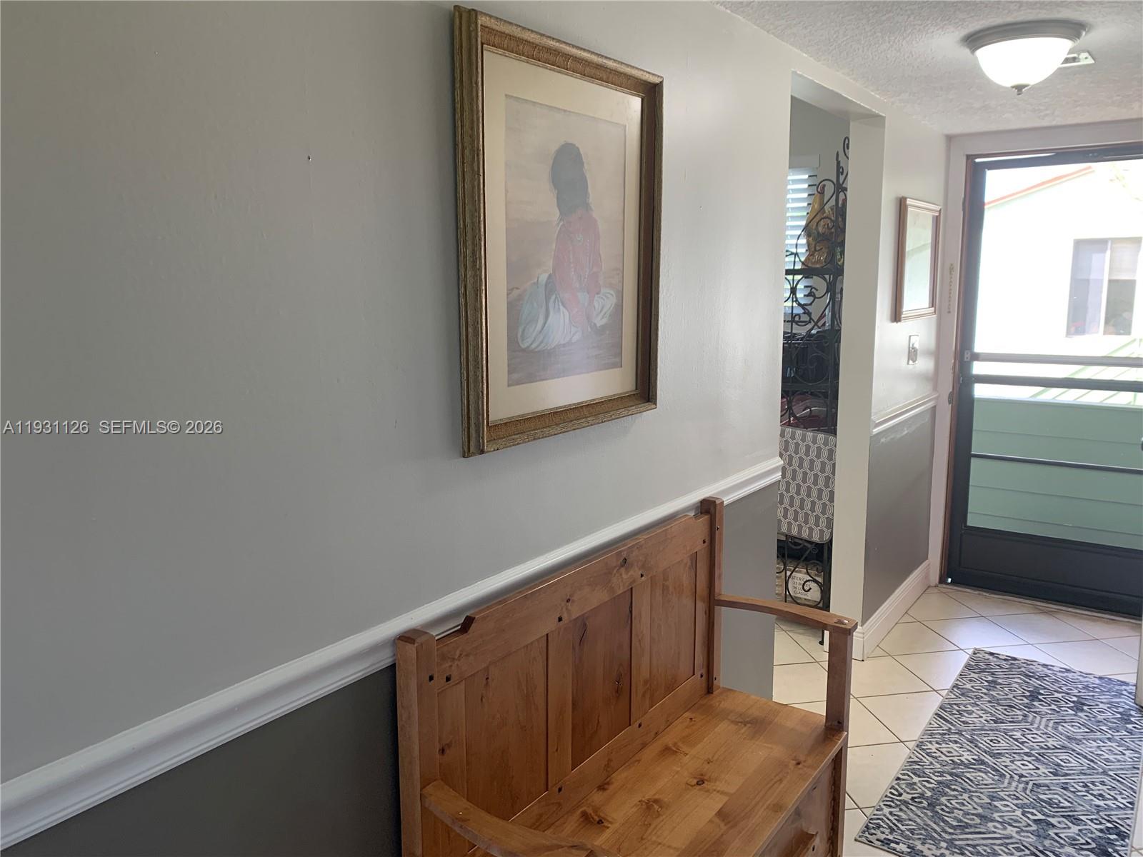 5463 Southeast Miles Grant Road, Unit 210 Stuart, FL 34997 - Photo 7 of 53 a hallway with painting on the wall and a potted plant