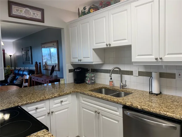 a kitchen with granite countertop a sink a stove and cabinets