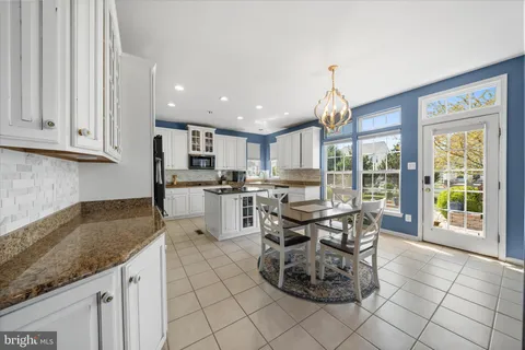 a kitchen with stainless steel appliances granite countertop a stove top oven a sink a dining table and chairs