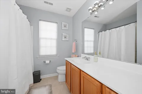 a spacious bathroom with a double vanity sink a toilet and a mirror